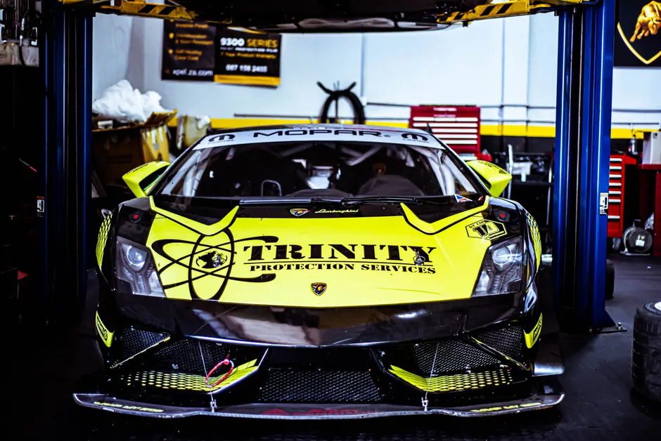 Front view of a vibrant yellow Lamborghini race car in an auto workshop, ready for action.