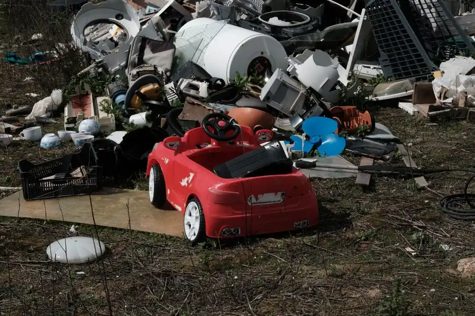 Red toy car amidst scattered debris, conveying abandonment and environmental neglect.